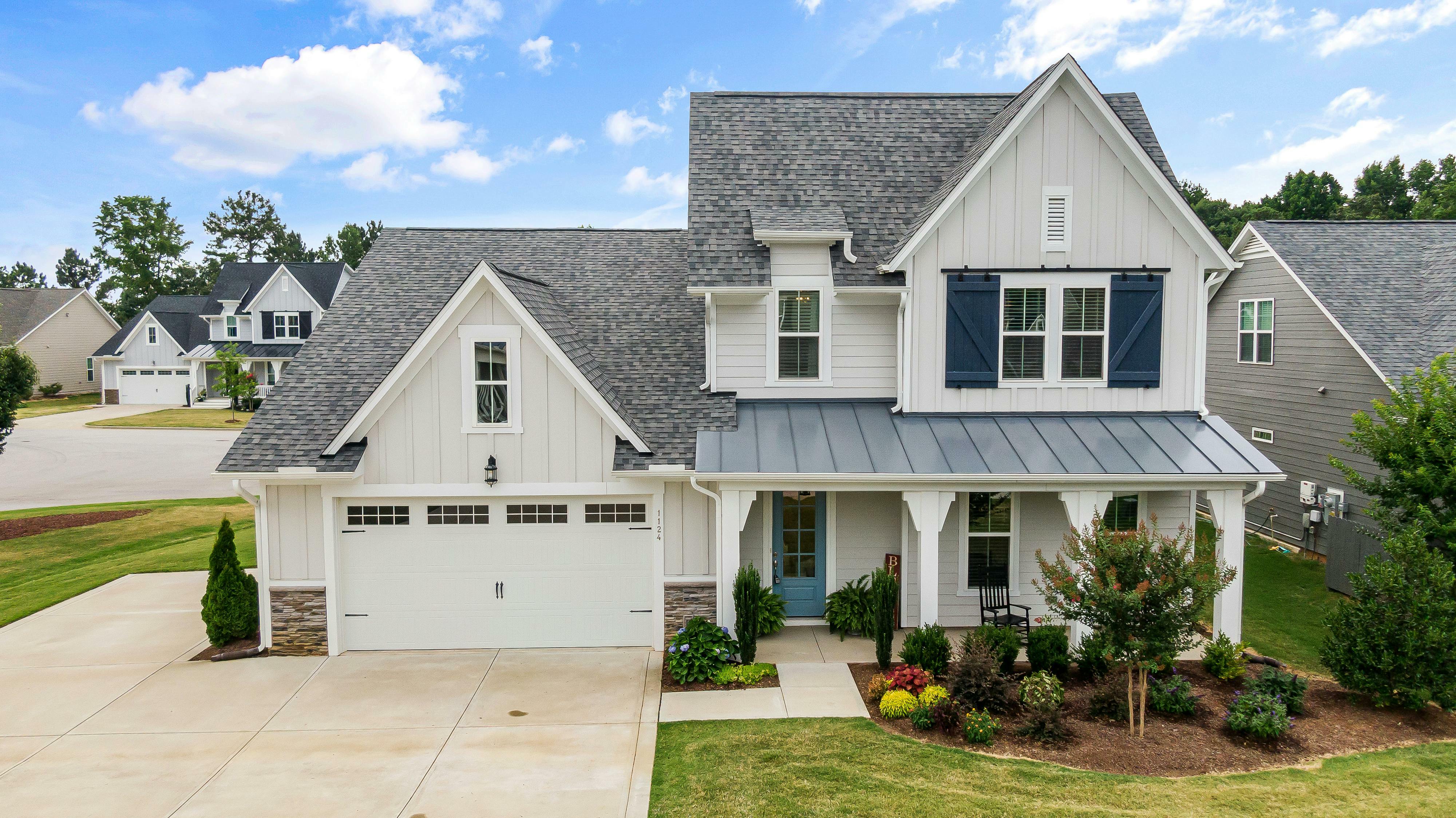 A modern home features beige siding, stone accents, blue shutters, a blue front door and white trim.