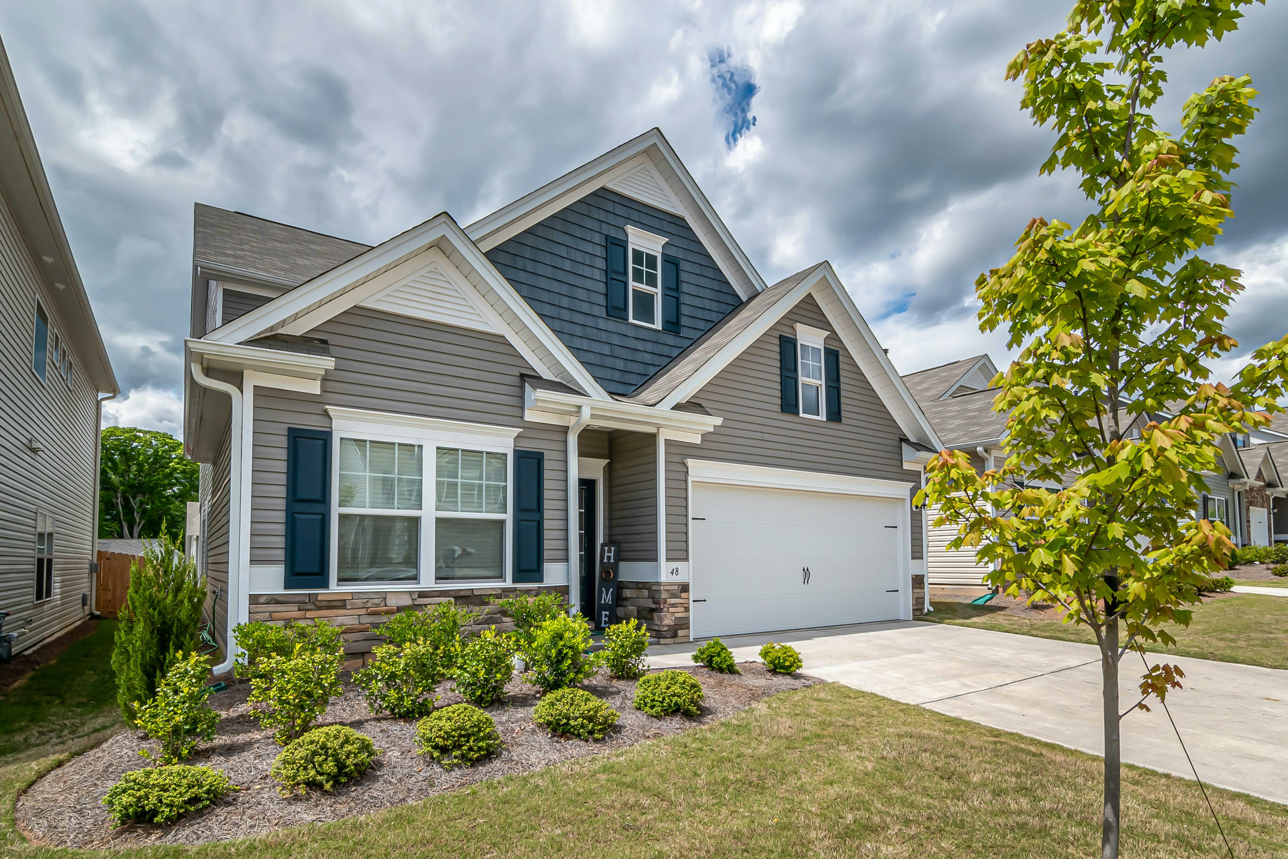 A two-story house has beige and blue siding with stone accents.