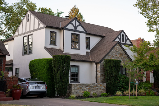 Exterior view of a Tudor-style home with dark decorative trim accents and a car parked in the driveway.